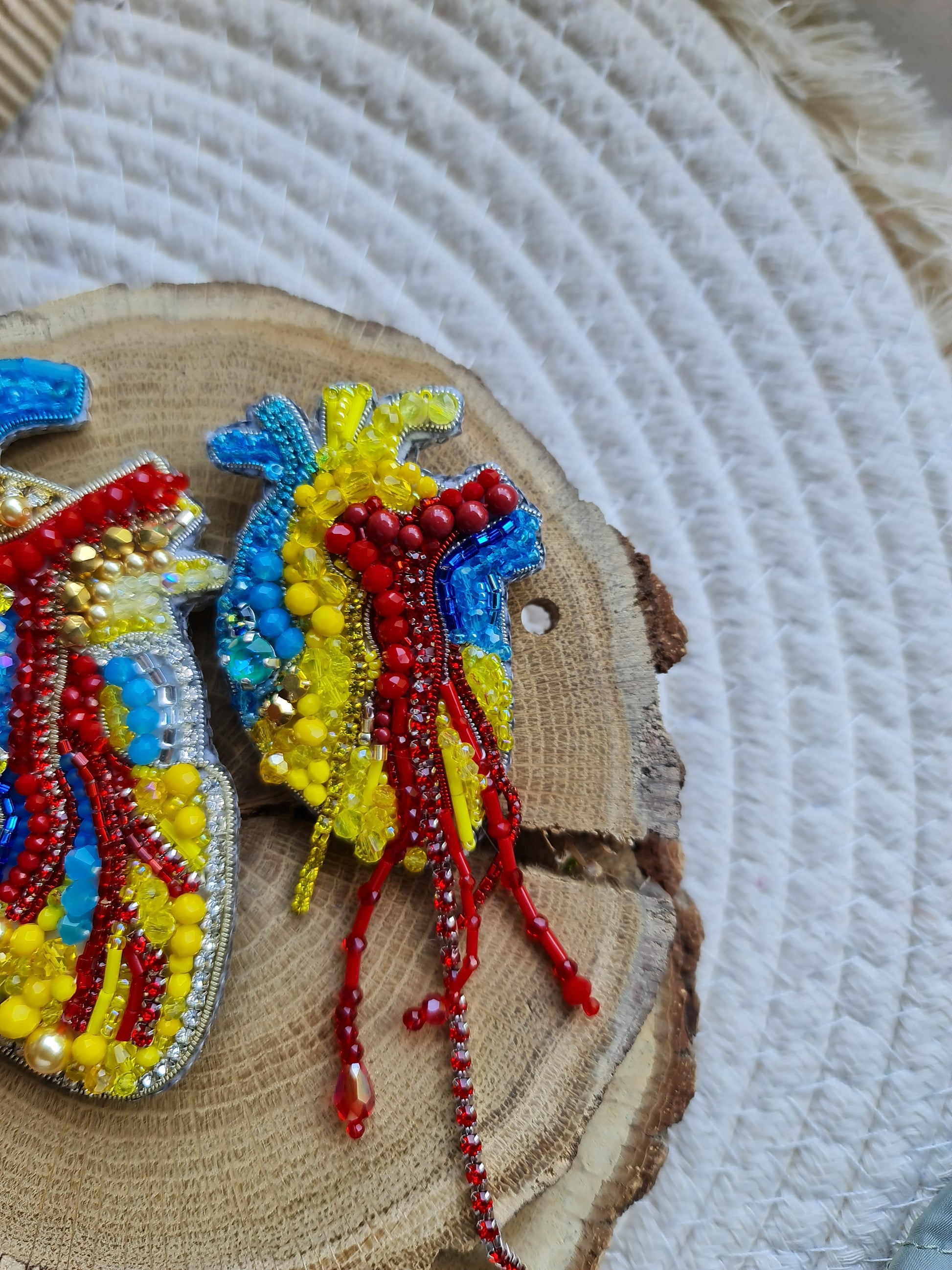 Anatomical heart beaded brooch hand embroidered with blue yellow and red beads, crystals, and sparkling chain details