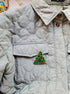 Quilted jacket with a Christmas tree patch on a neutral background