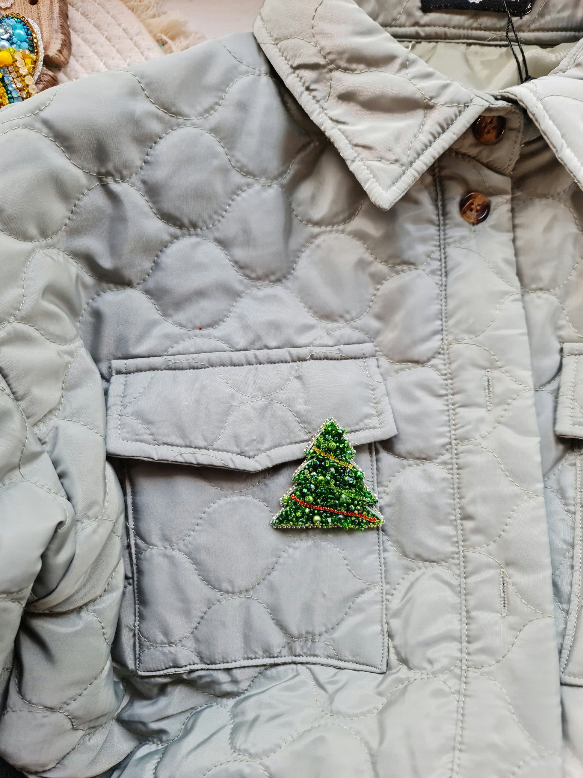 Quilted jacket with a Christmas tree patch on a neutral background