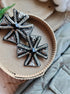 Decorative cross-shaped brooches on a wooden surface with a natural background.