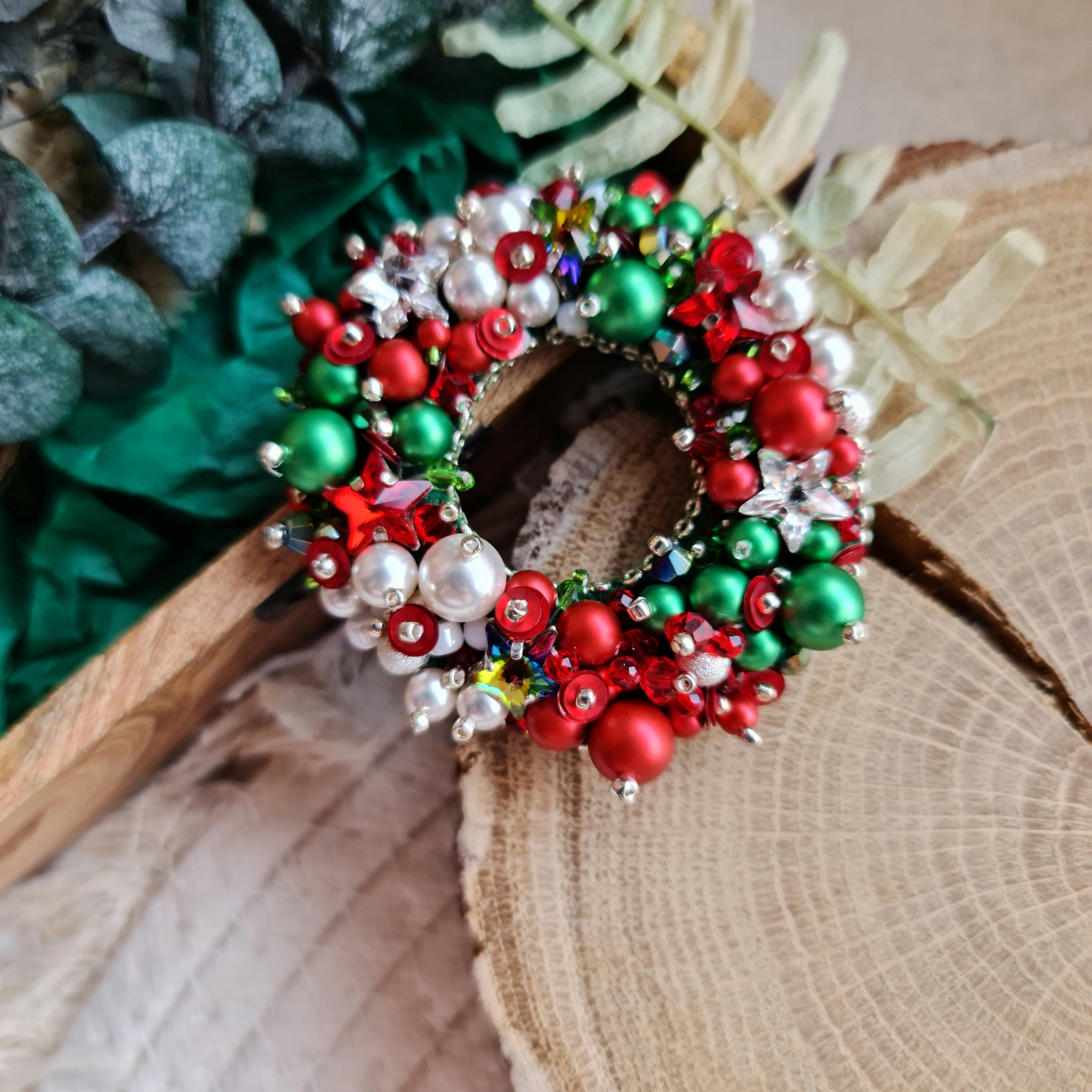 Decorative wreath with red, green, and white beads on a wooden surface