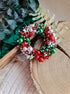 Decorative wreath with red, green, and white beads on a wooden surface