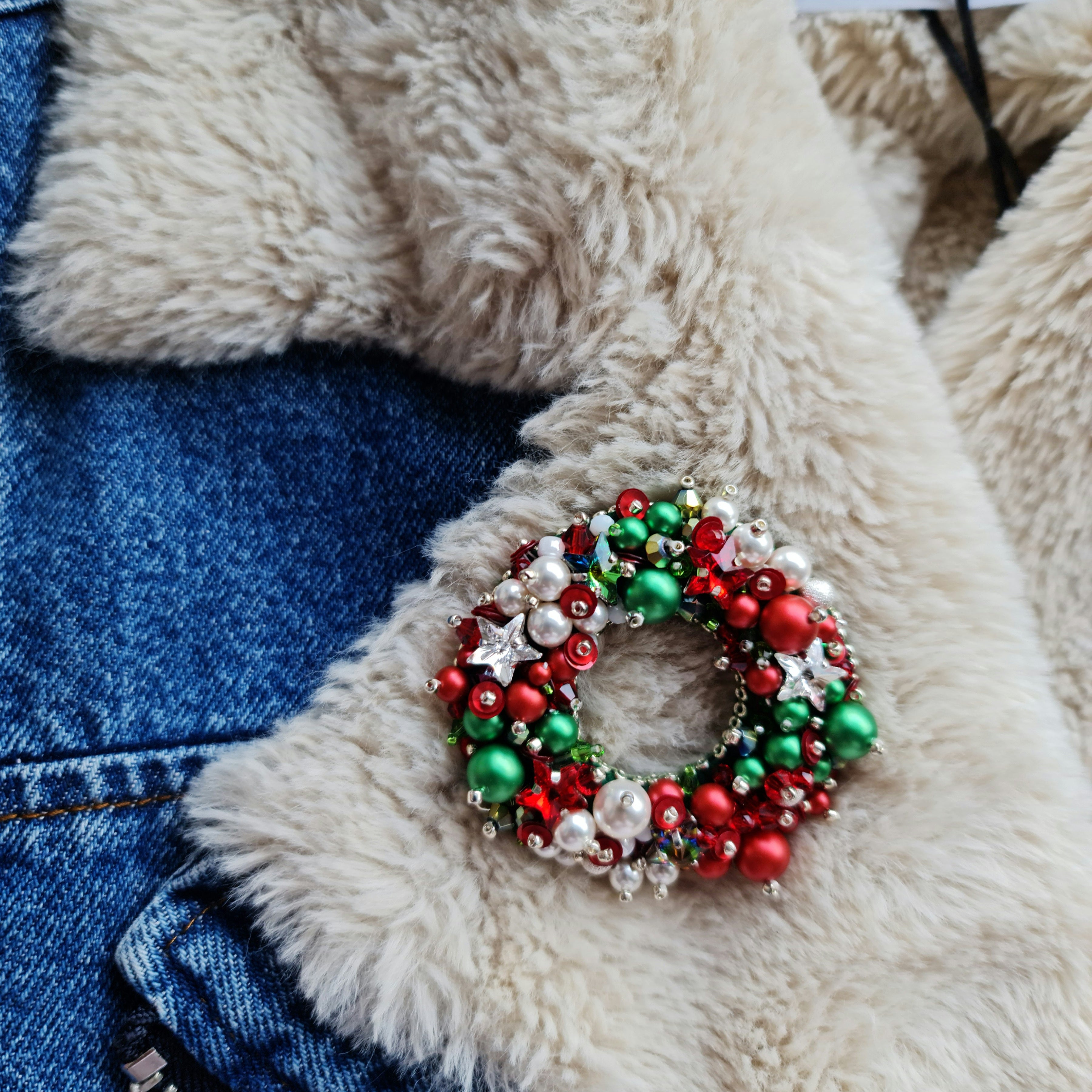 Handmade Christmas wreath brooch embroidered with red, green and white beads, pearls, sequins and crystals, festive holiday pin inspired by traditional Christmas decorations.