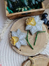 Decorative flower brooches on a wooden surface with a wooden box and stones in the background.
