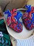 Two beaded heart-shaped brooches on a wooden surface