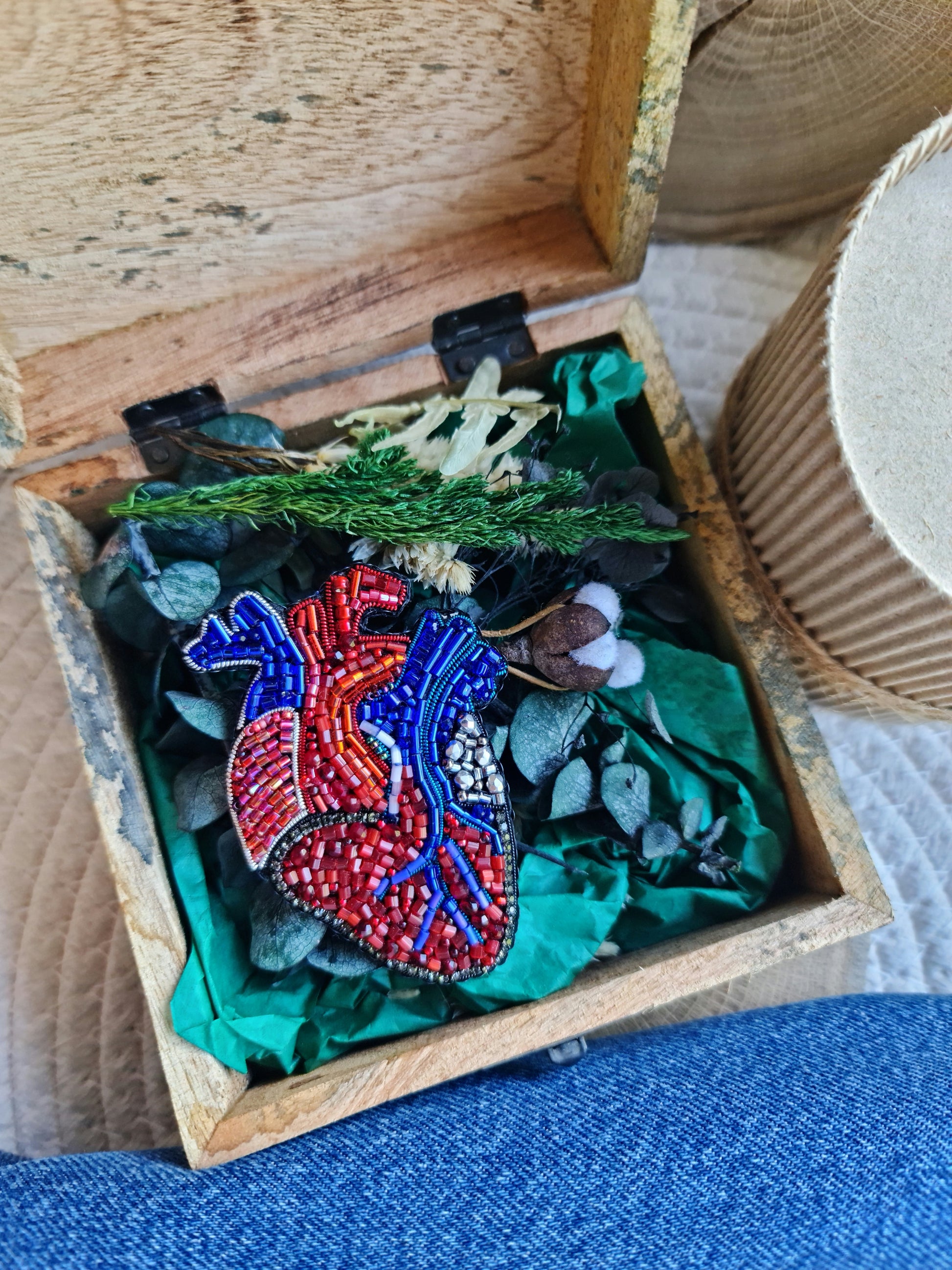Decorative heart-shaped object with beadwork in a wooden box