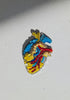 Close-up of the anatomical heart brooch showing detailed stitching and vibrant embroidered patterns.