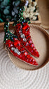 Decorative red chili pepper brooch with gemstones on a textured surface