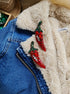 Red chili pepper earrings on a denim jacket with a fluffy beige surface.