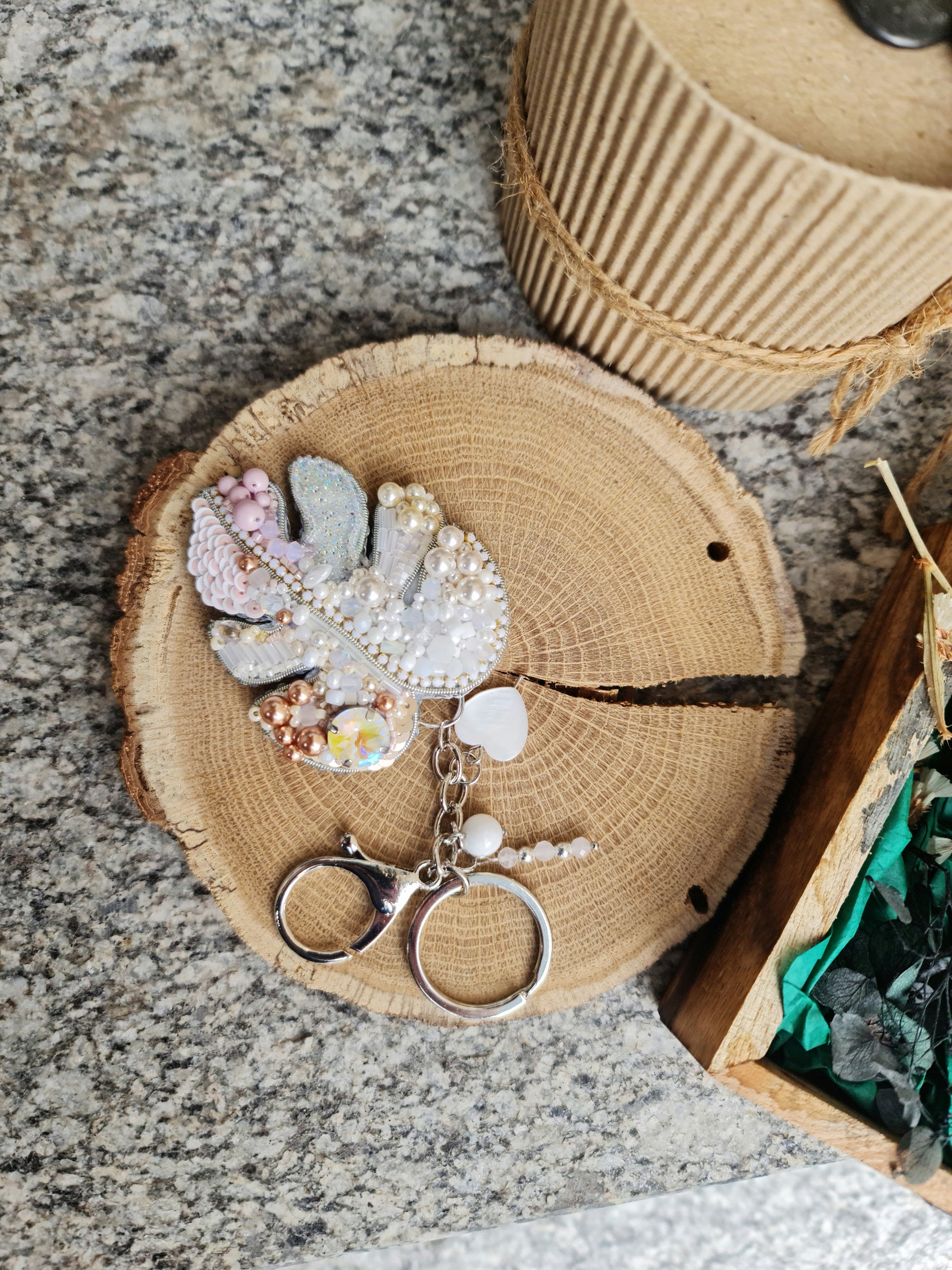 Decorative keychain with leaf and heart designs on a wooden coaster.