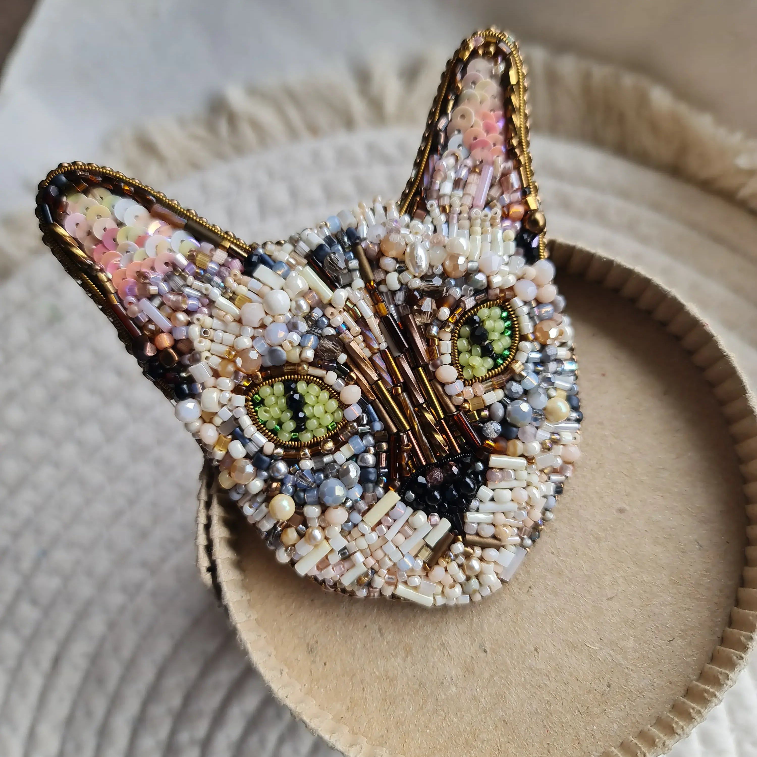 Beaded cat face brooch on a textured surface