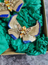 Gold and blue butterfly brooches on green fabric with a dark background