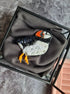 Sequined puffin brooch on a gray fabric background