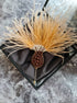 Decorative hair stick with feather and bead details in a black box on a gray marble surface