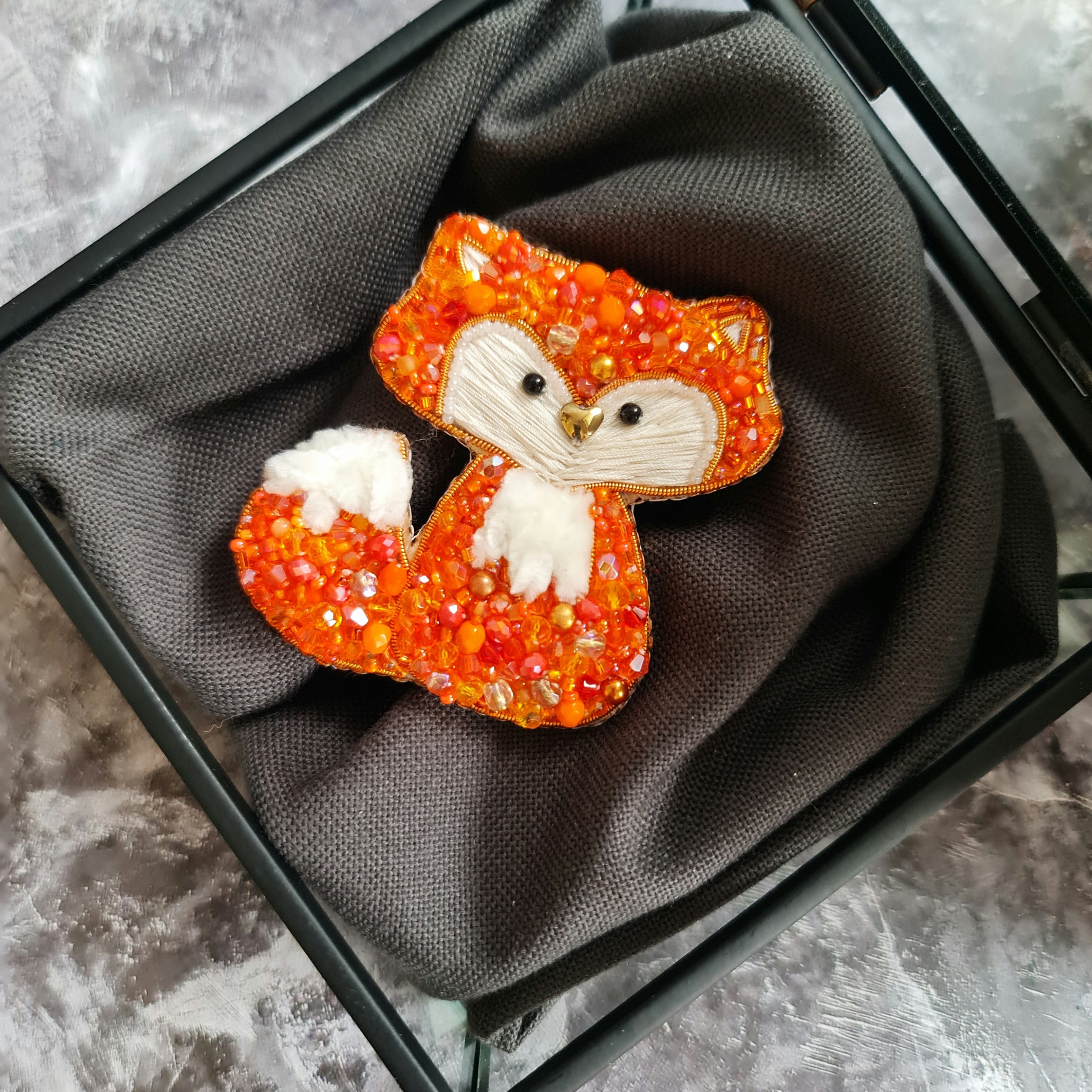 Handmade fox beaded brooch in orange tones with fluffy white tail detail and embroidered face