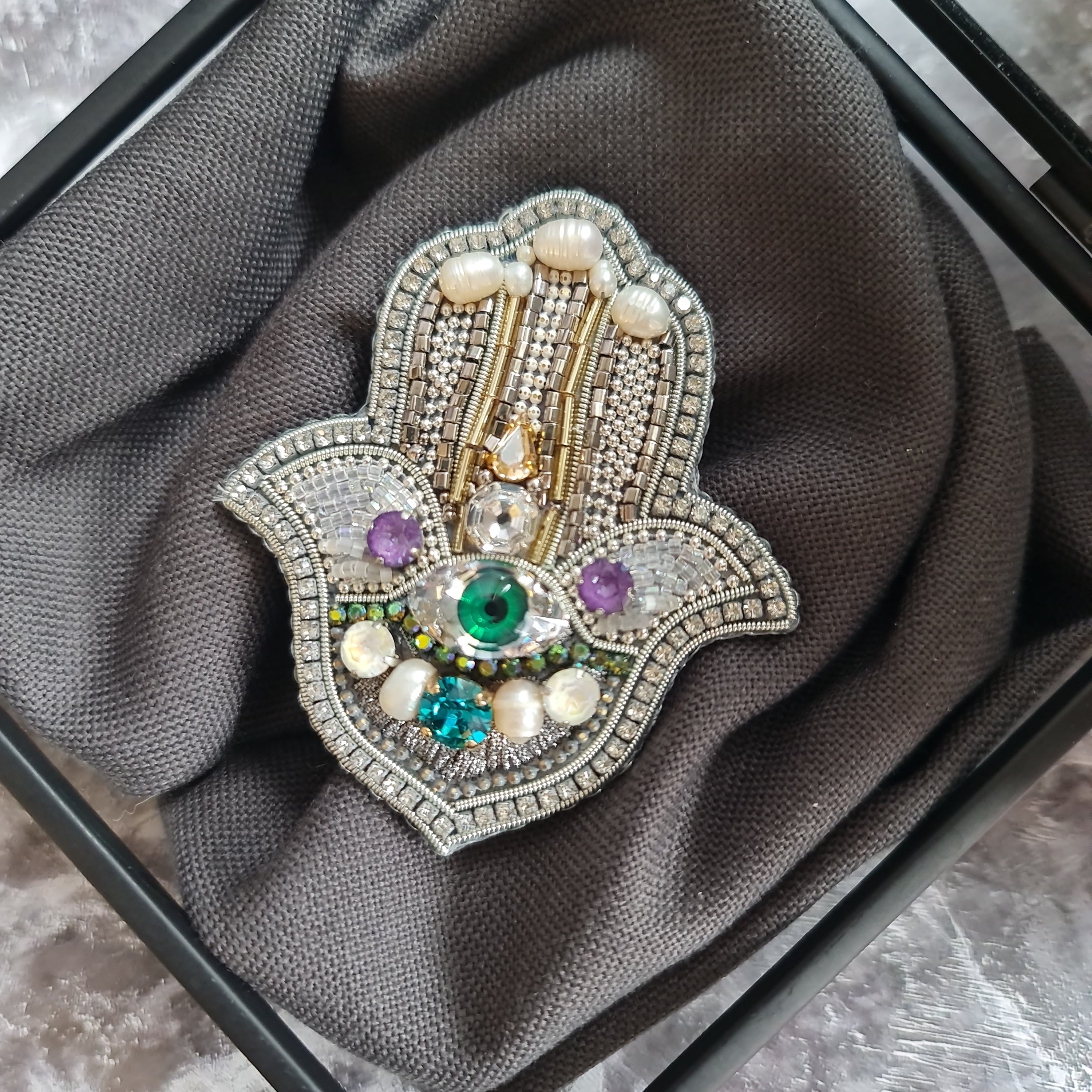 Decorative brooch with gemstones on a gray fabric background