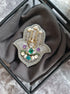 Decorative brooch with gemstones on a gray fabric background