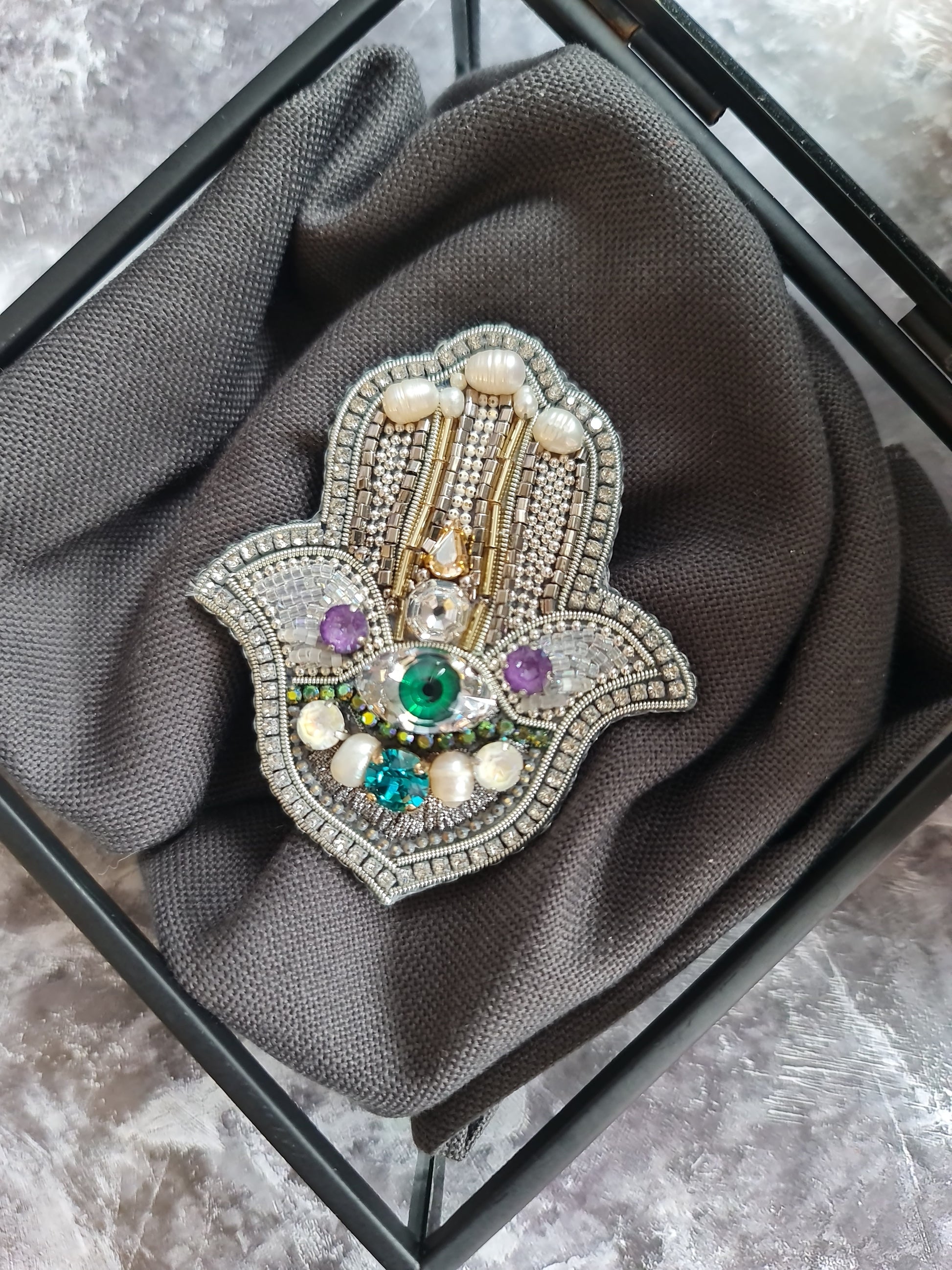 Decorative brooch with gemstones on a gray fabric background