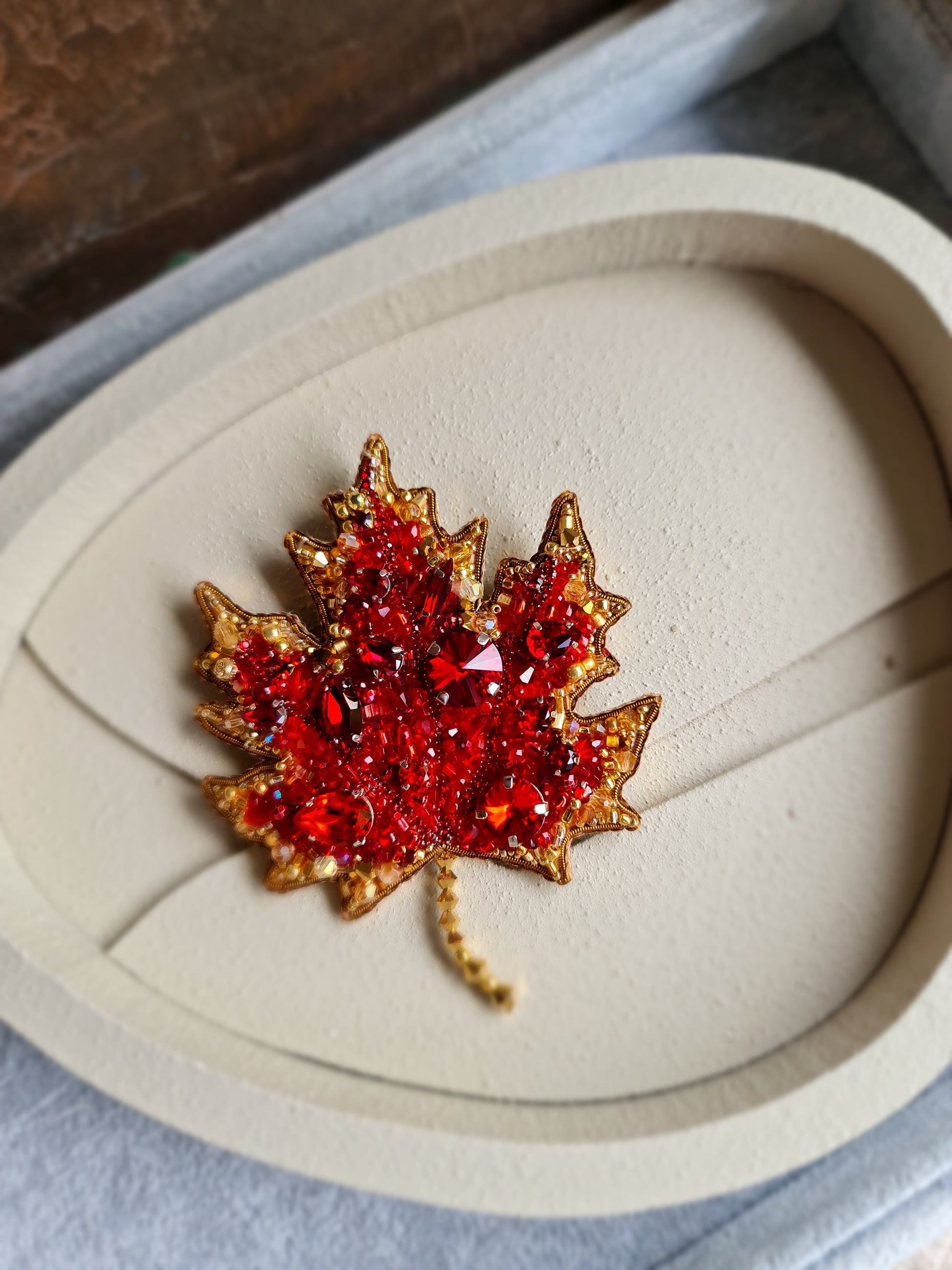 Maple leaf brooch with red gemstones on a heart-shaped display box