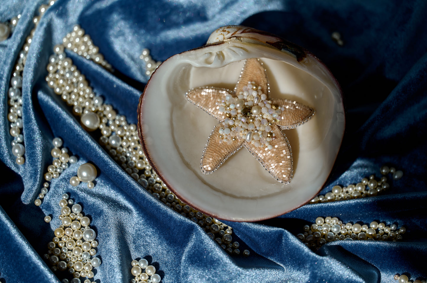Model wearing the Stellar Seas Starfish Brooch as a statement accessory, highlighting its ocean-inspired design with warm peach, beige, and golden tones.