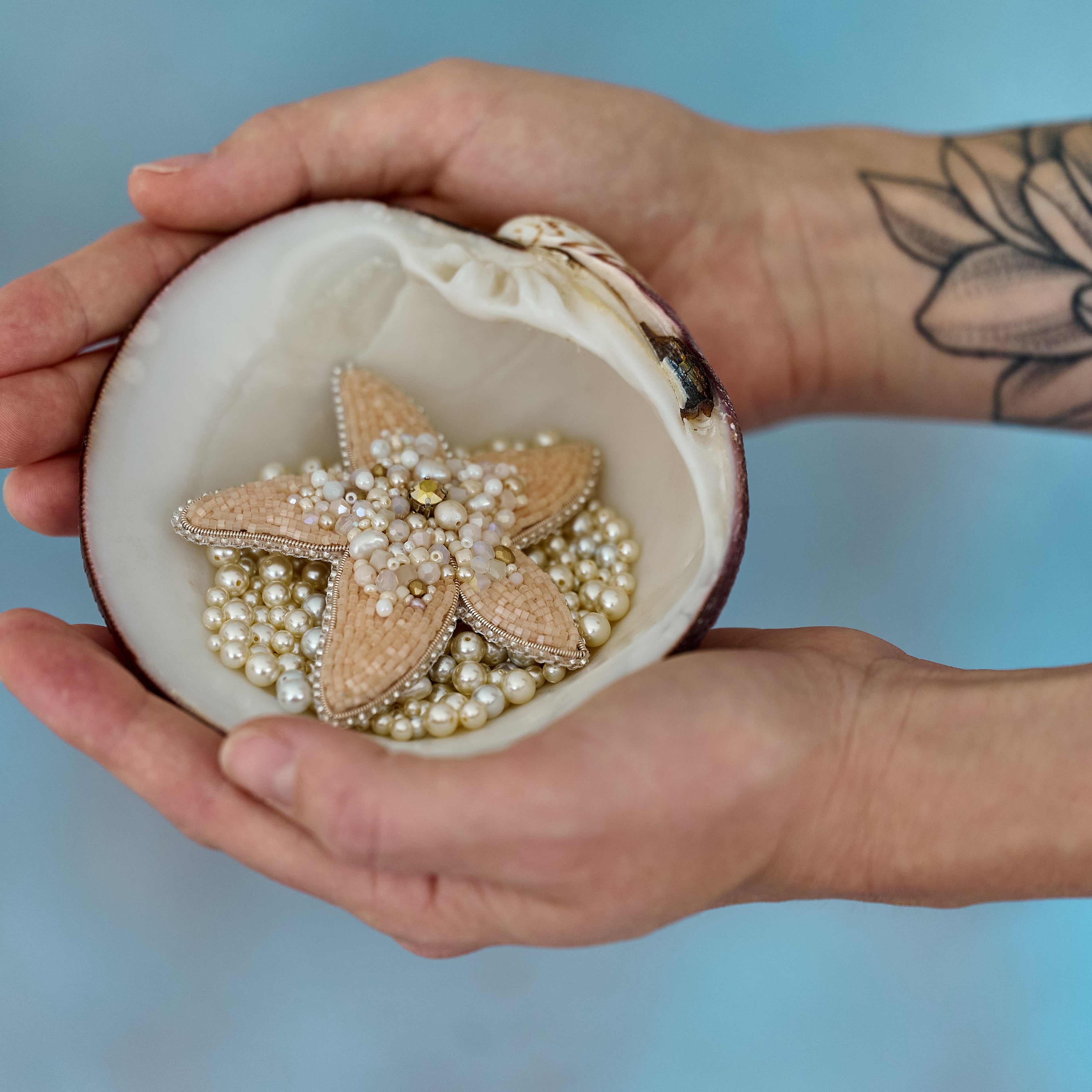 Handcrafted Stellar Seas Starfish Brooch featuring intricate embroidery with Japanese beads, assorted beads, shimmering crystals, and pearls in warm peach, beige, and golden hues. Measures 3.51 inches by 3.12 inches (9 cm x 8 cm).