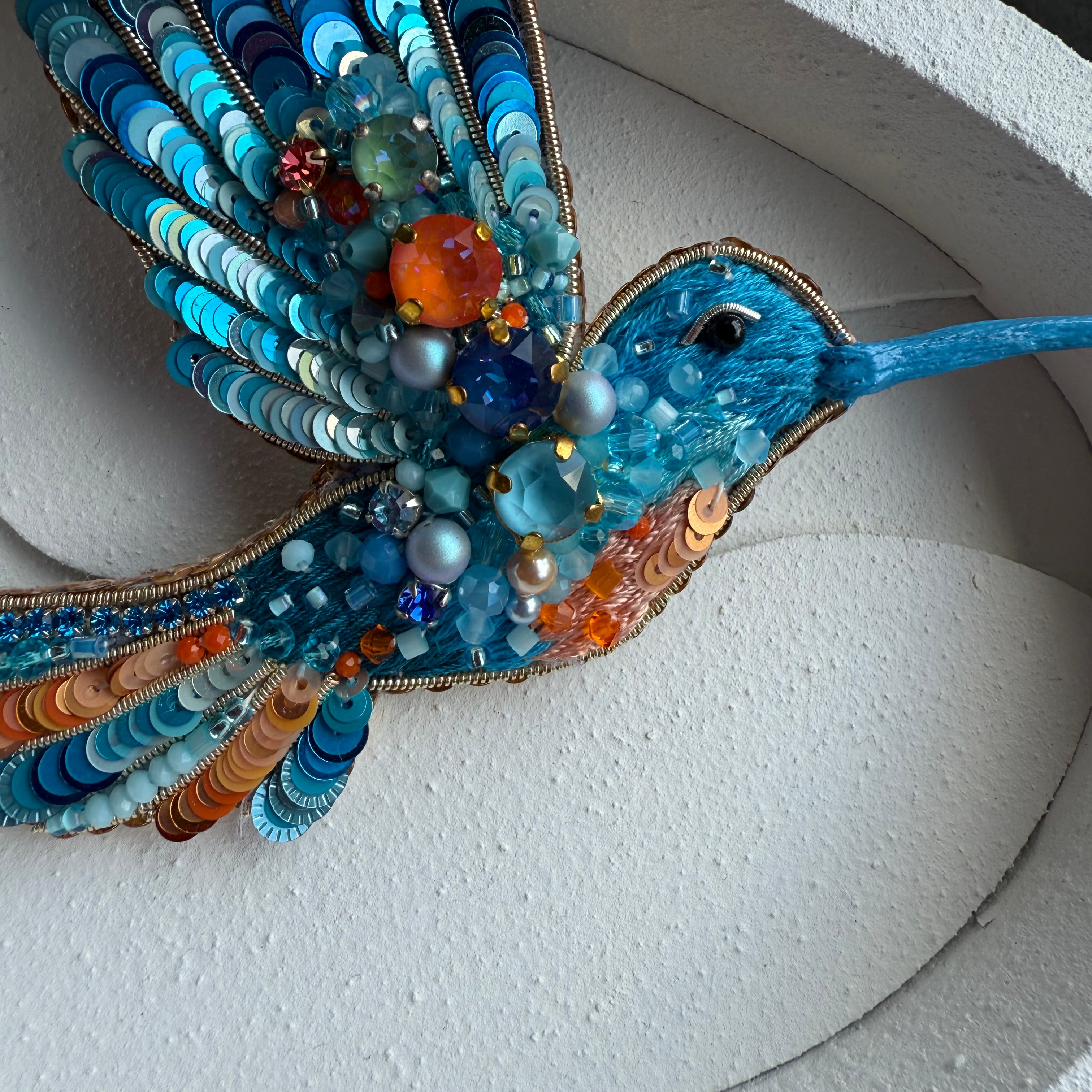 Decorative beaded hummingbird sculpture on a white background