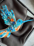 Colorful beaded hummingbird on a dark fabric background