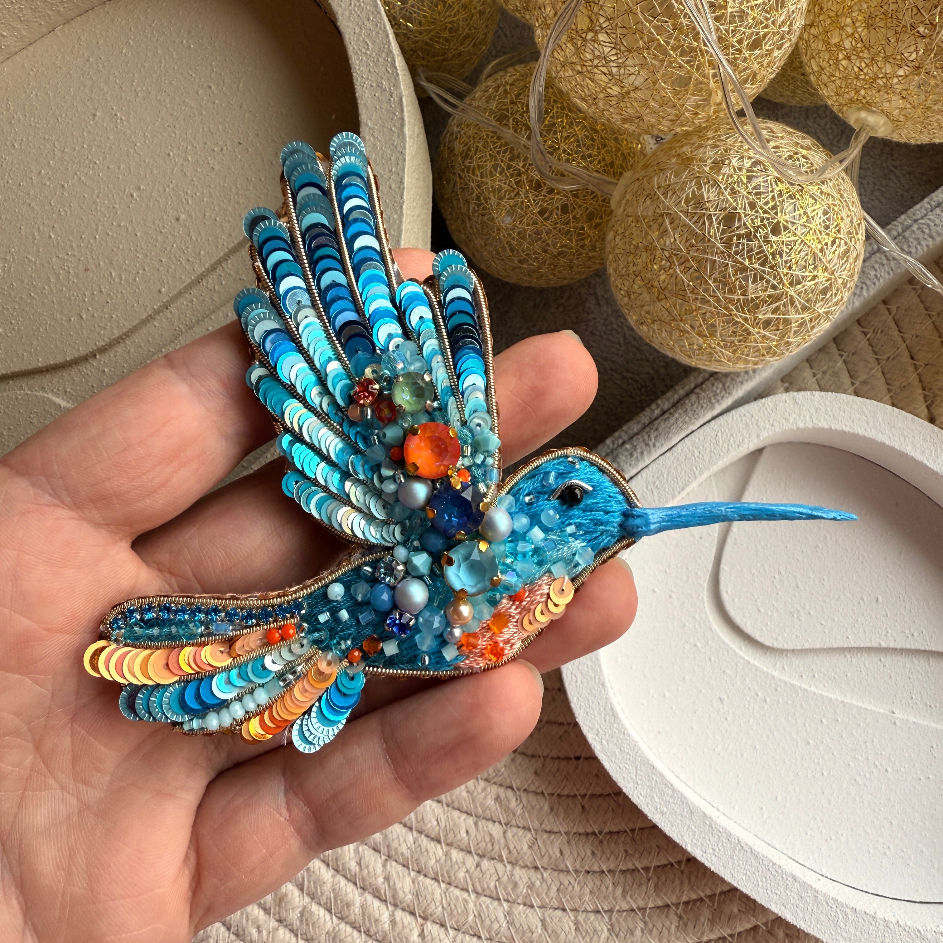Blue hummingbird beaded brooch hand embroidered with turquoise sequins, orange accents, crystals, beads, and sparkling wing details