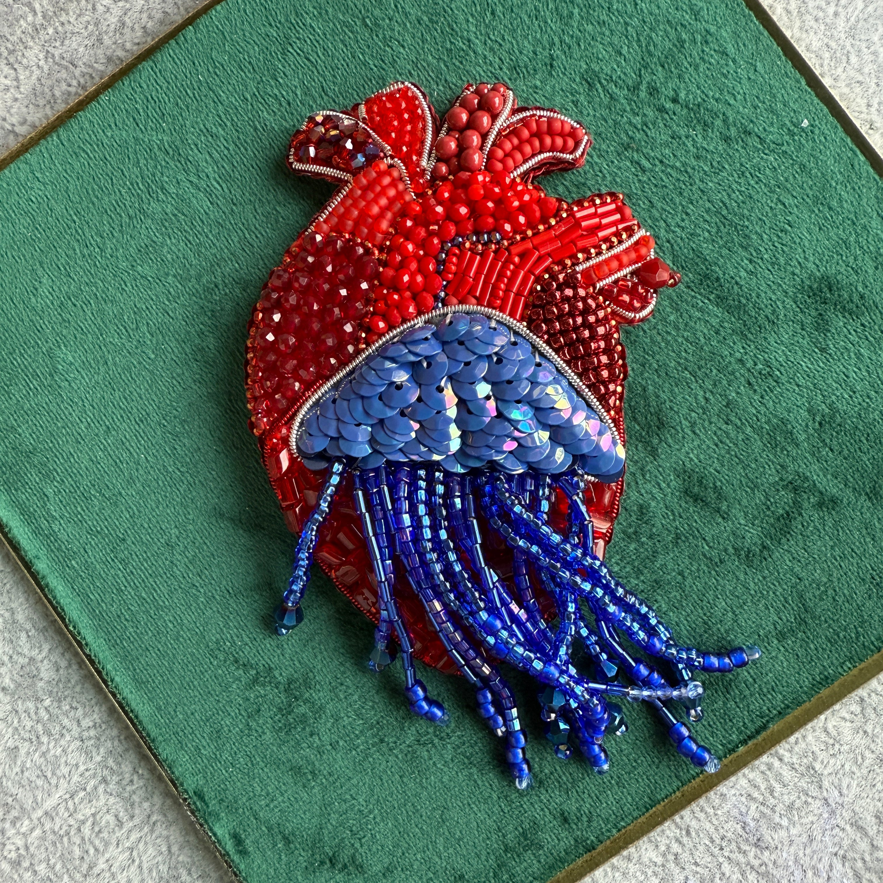 Red and blue beaded crab on a green fabric background