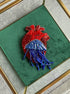 Decorative brooch with red and blue elements on a green background