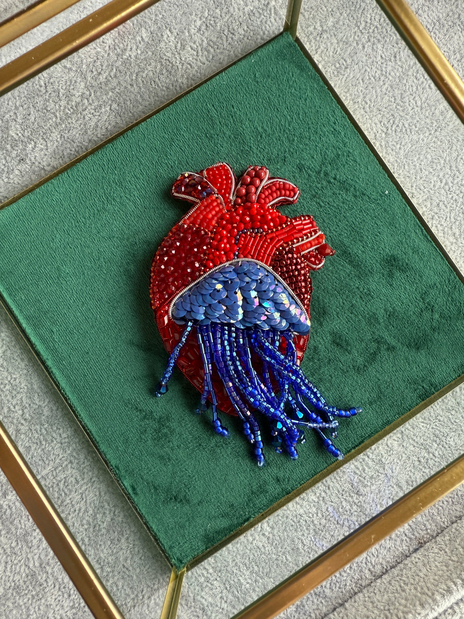 Decorative brooch with red and blue elements on a green background