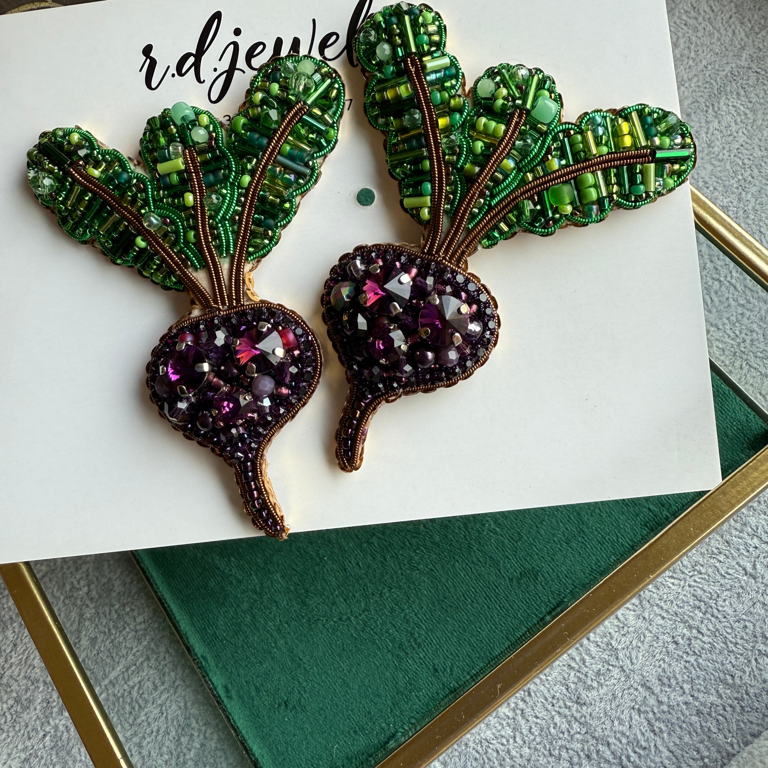 Handmade purple beet earrings with green leafy tops and sparkling violet crystals, embroidered with beads and inspired by fresh garden vegetables.