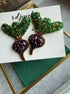 Handmade purple beet earrings with green leafy tops and sparkling violet crystals, embroidered with beads and inspired by fresh garden vegetables.