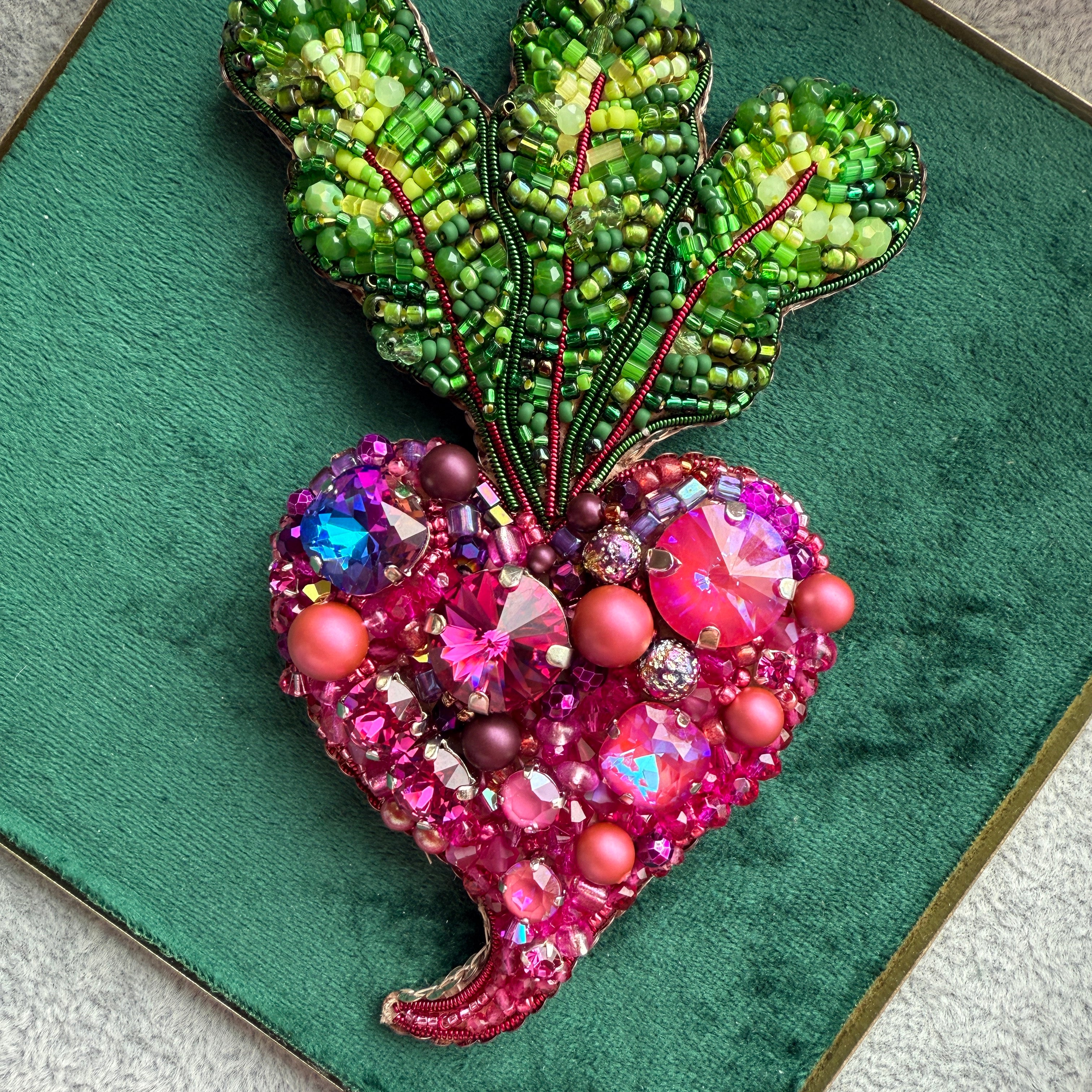 Decorative brooches with green leaf-like design and pink flower-like design on a green background
