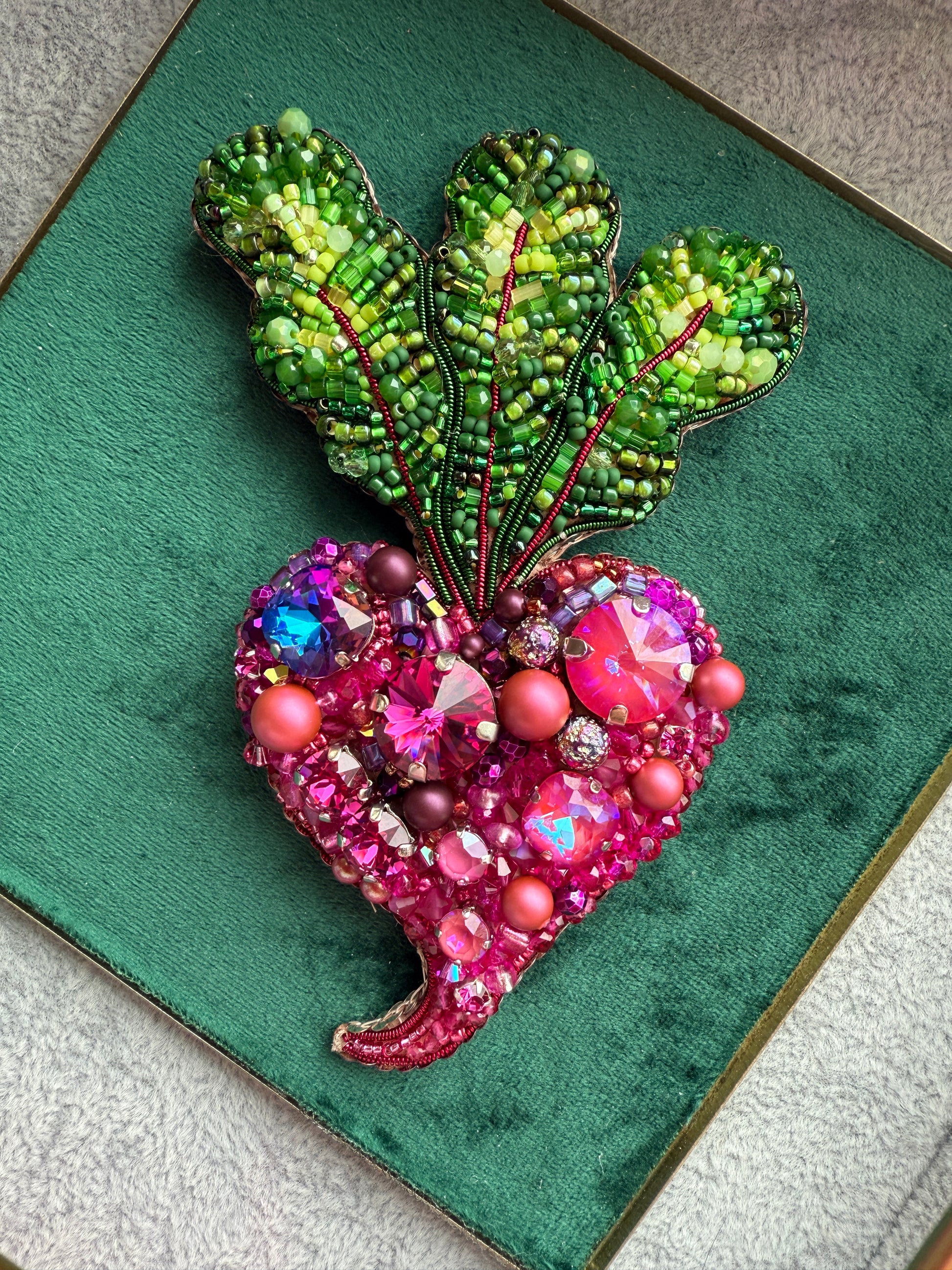 Decorative brooches with green leaf-like design and pink flower-like design on a green background