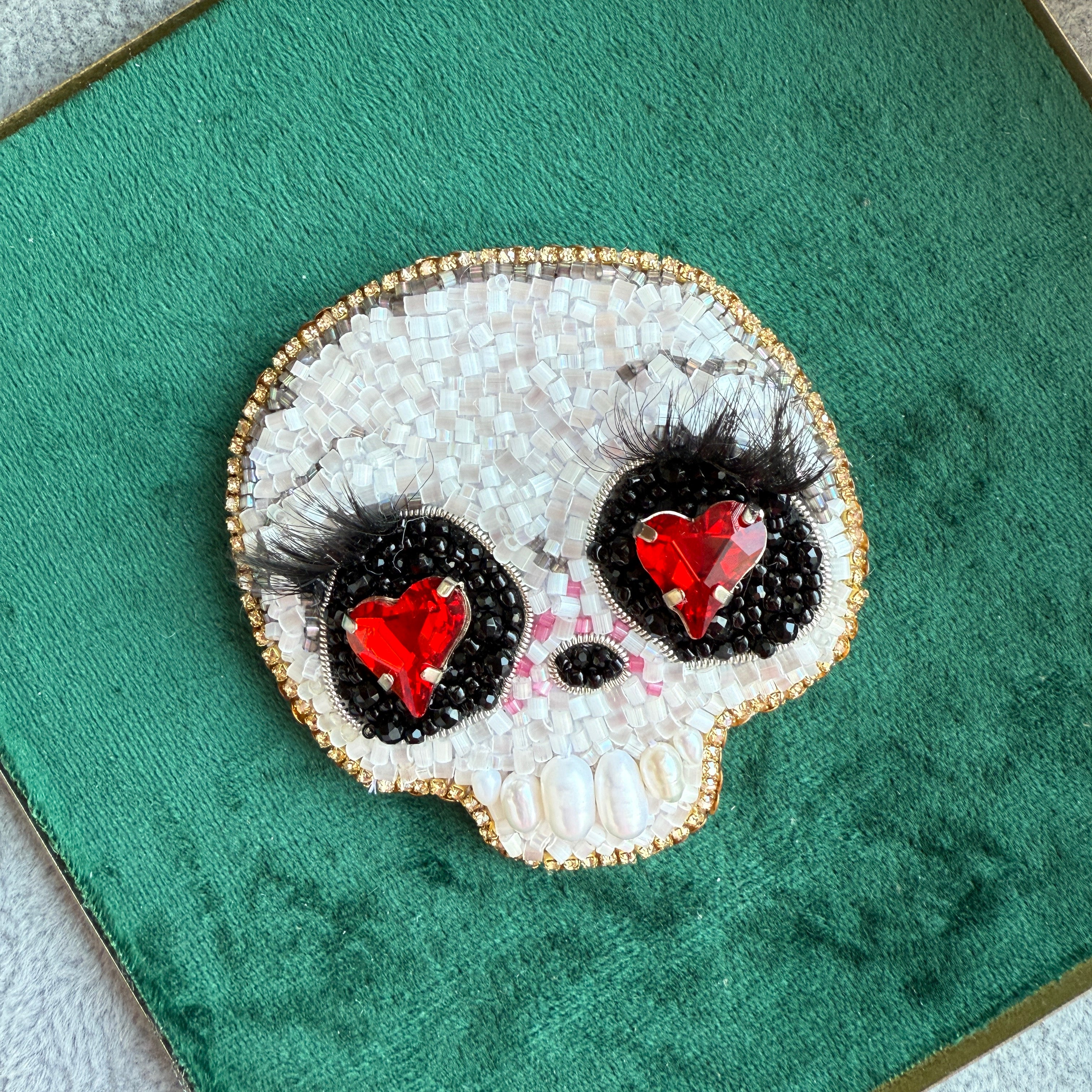 Decorative brooch with red gemstones and black accents on a green background