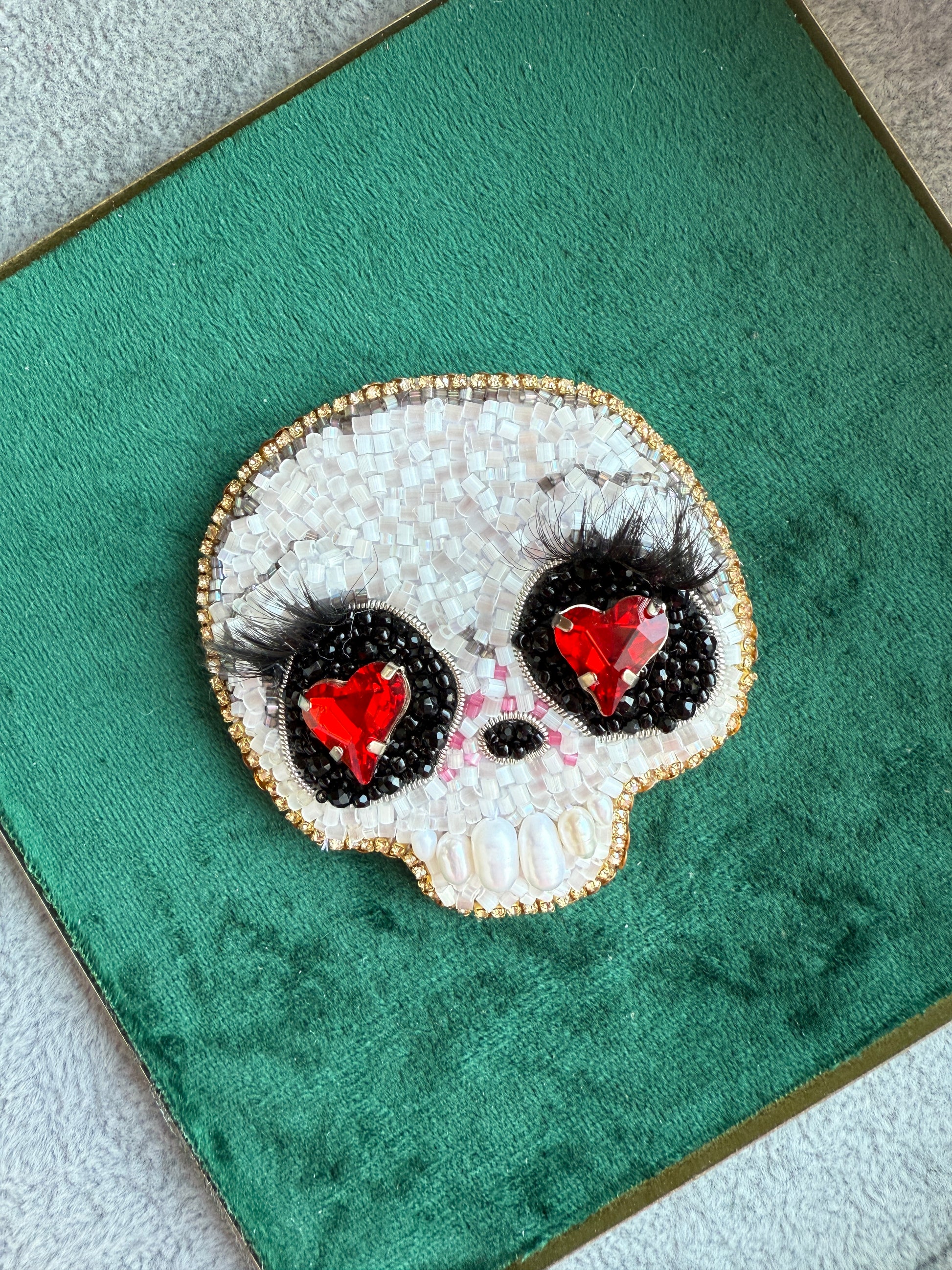 Decorative brooch with red gemstones and black accents on a green background