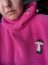 Close-up of a pink hoodie with a mushroom emblem on the chest.
