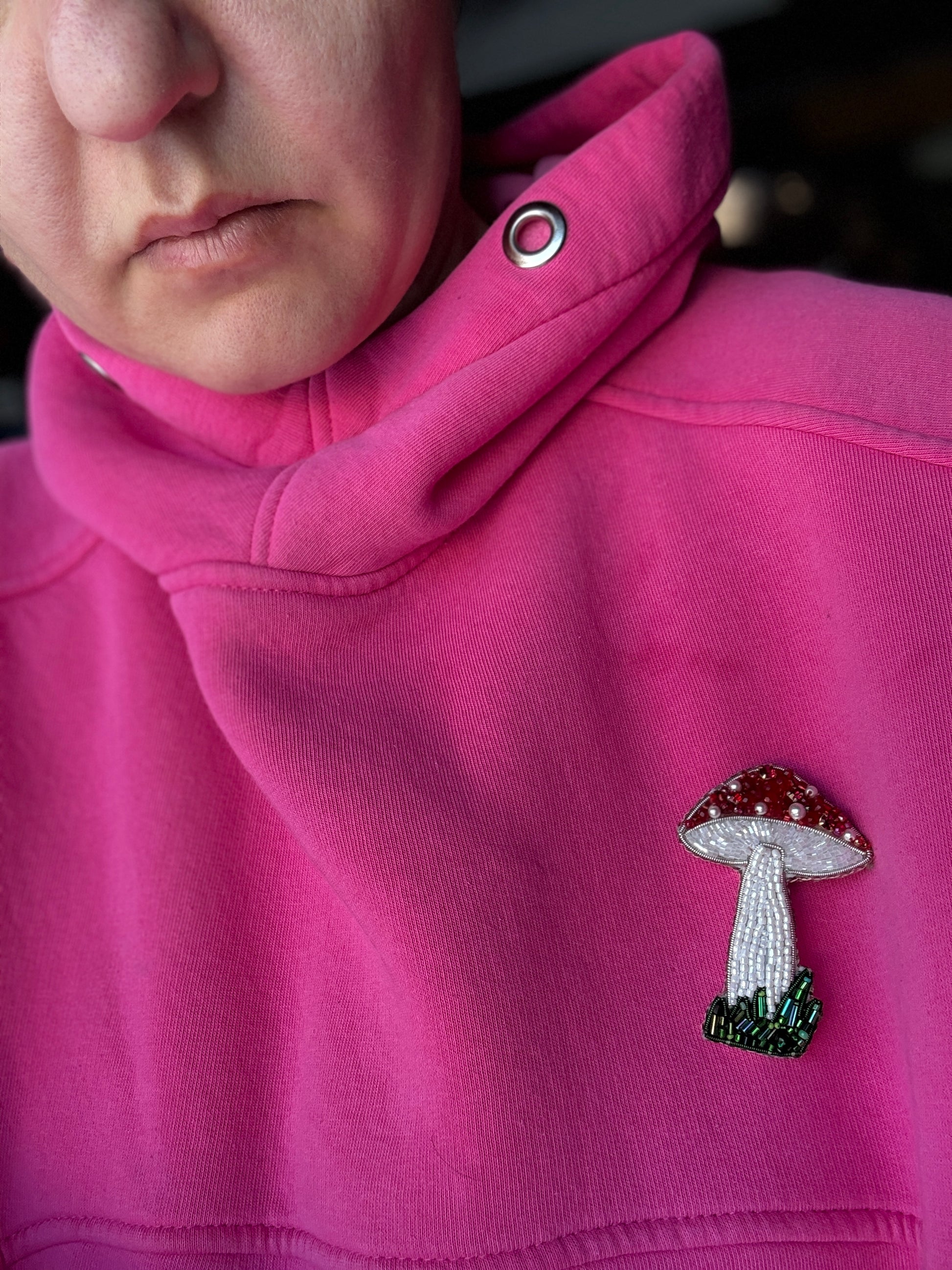 Close-up of a pink hoodie with a mushroom emblem on the chest.