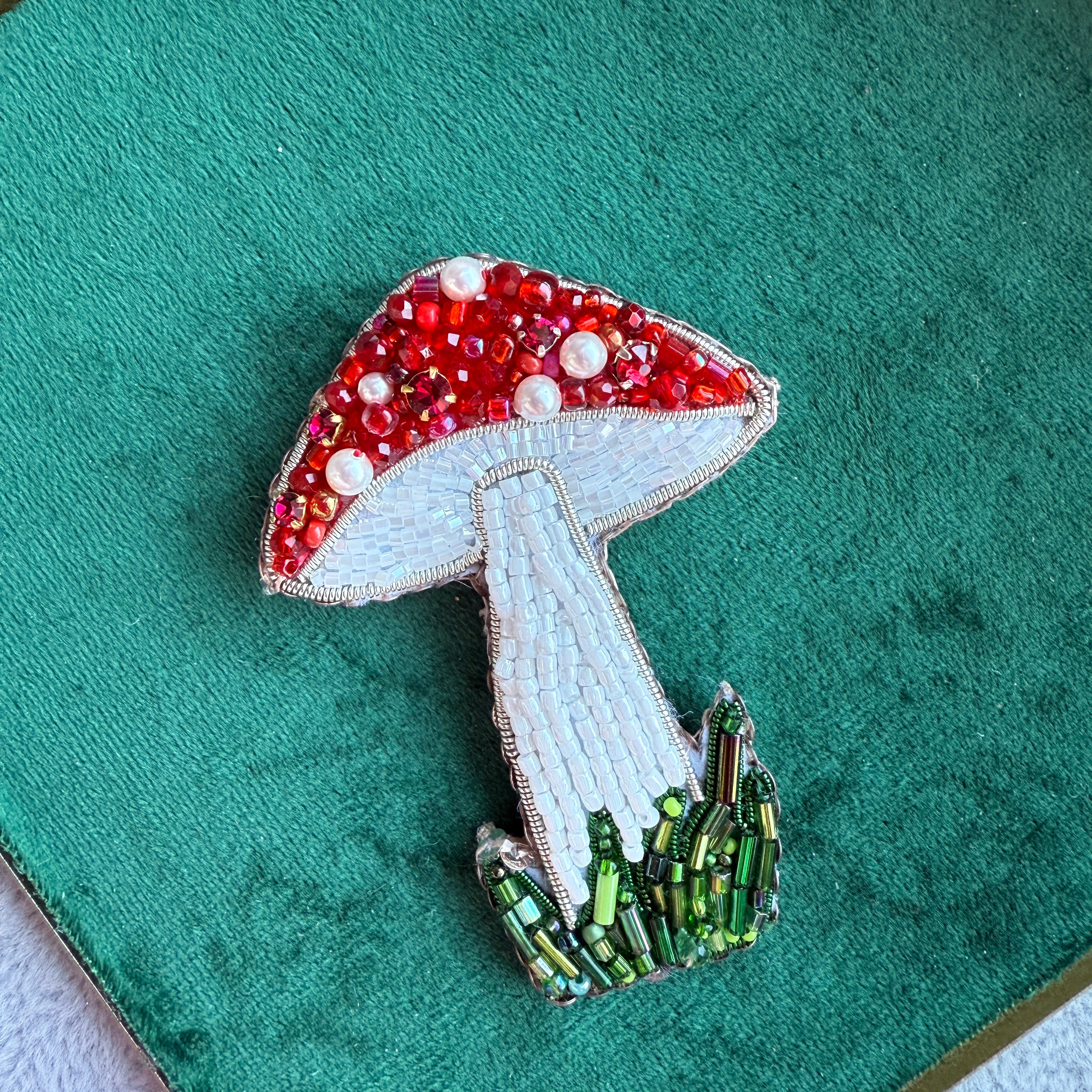 Decorative brooch with red, white, and green colors on a green fabric background