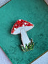 Decorative brooch with red, white, and green colors on a green fabric background