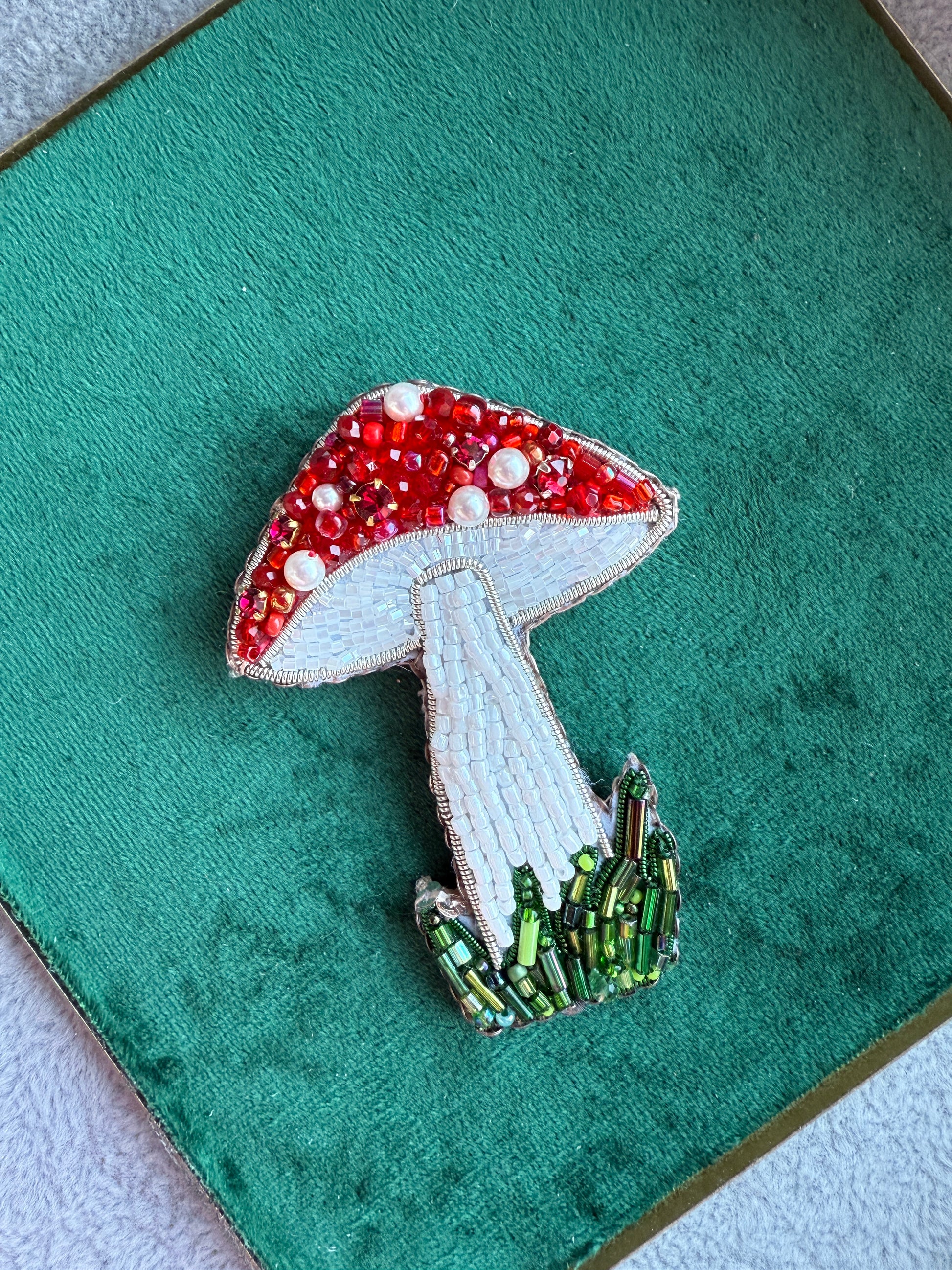 Decorative brooch with red, white, and green colors on a green fabric background