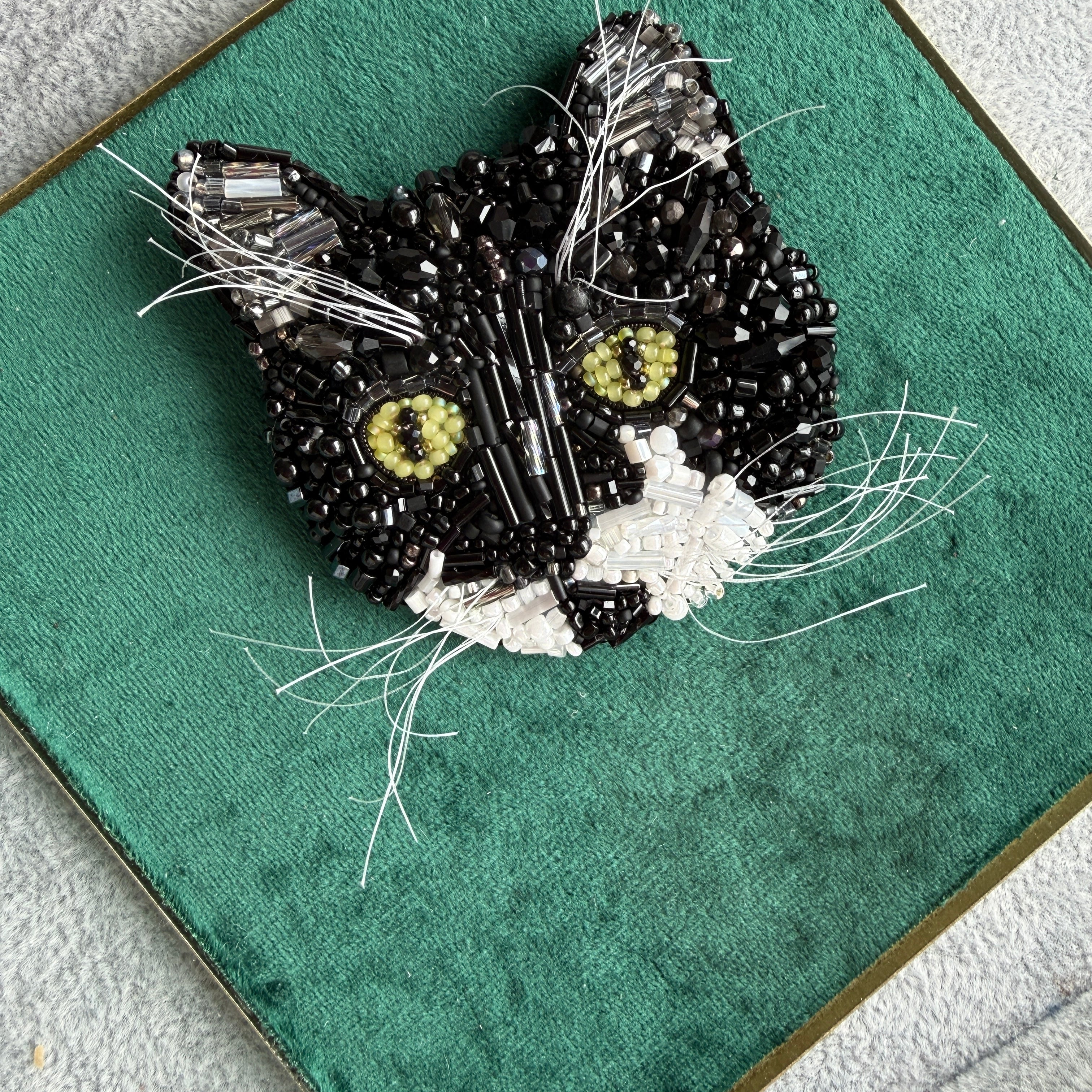 Custom black and white cat portrait beaded brooch hand embroidered with black beads, white whiskers, green eyes, crystals, and detailed pet embroidery