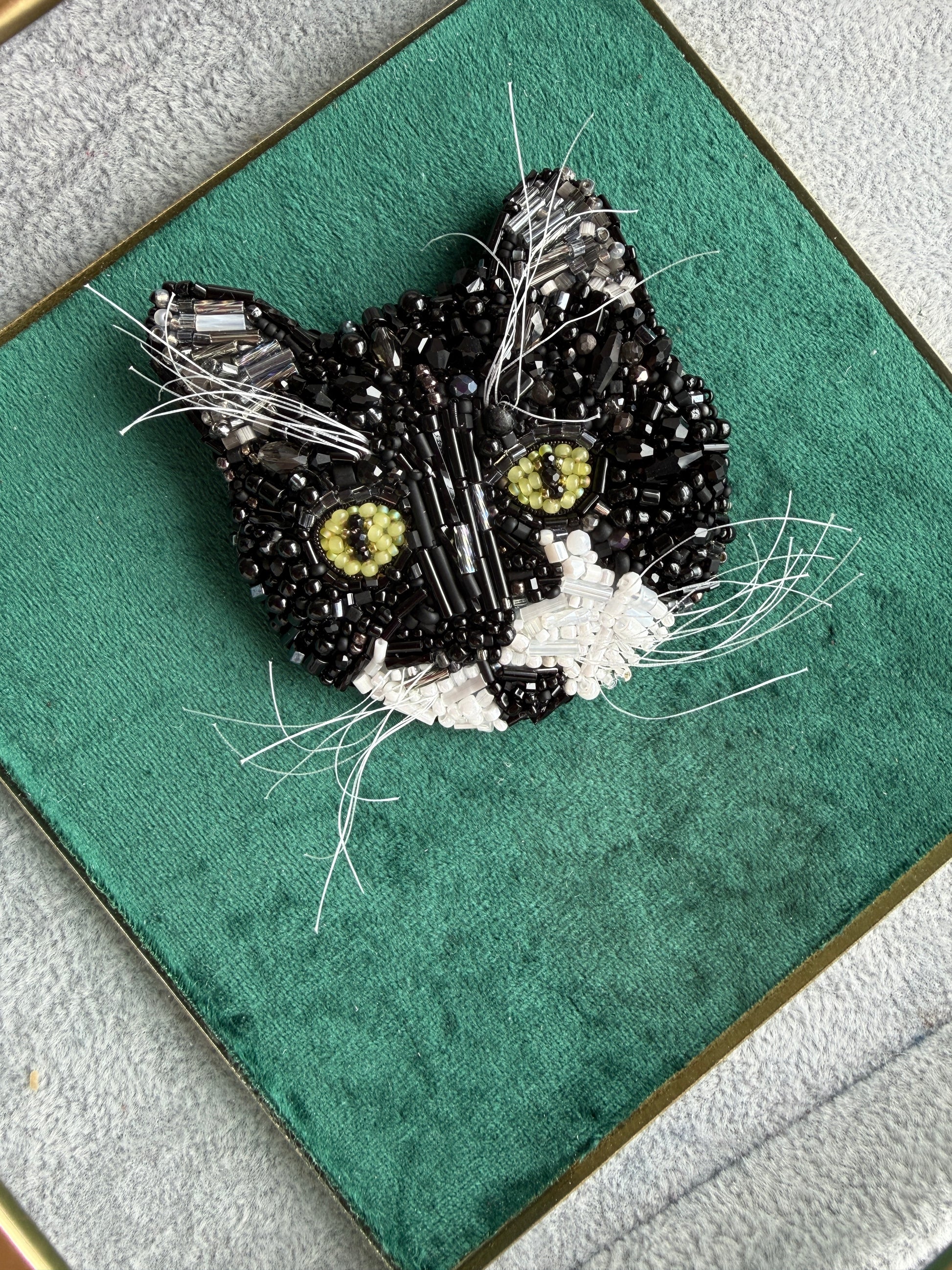 Custom black and white cat portrait beaded brooch hand embroidered with black beads, white whiskers, green eyes, crystals, and detailed pet embroidery