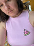 Person wearing a pink sleeveless top with a decorative watermelon patch.