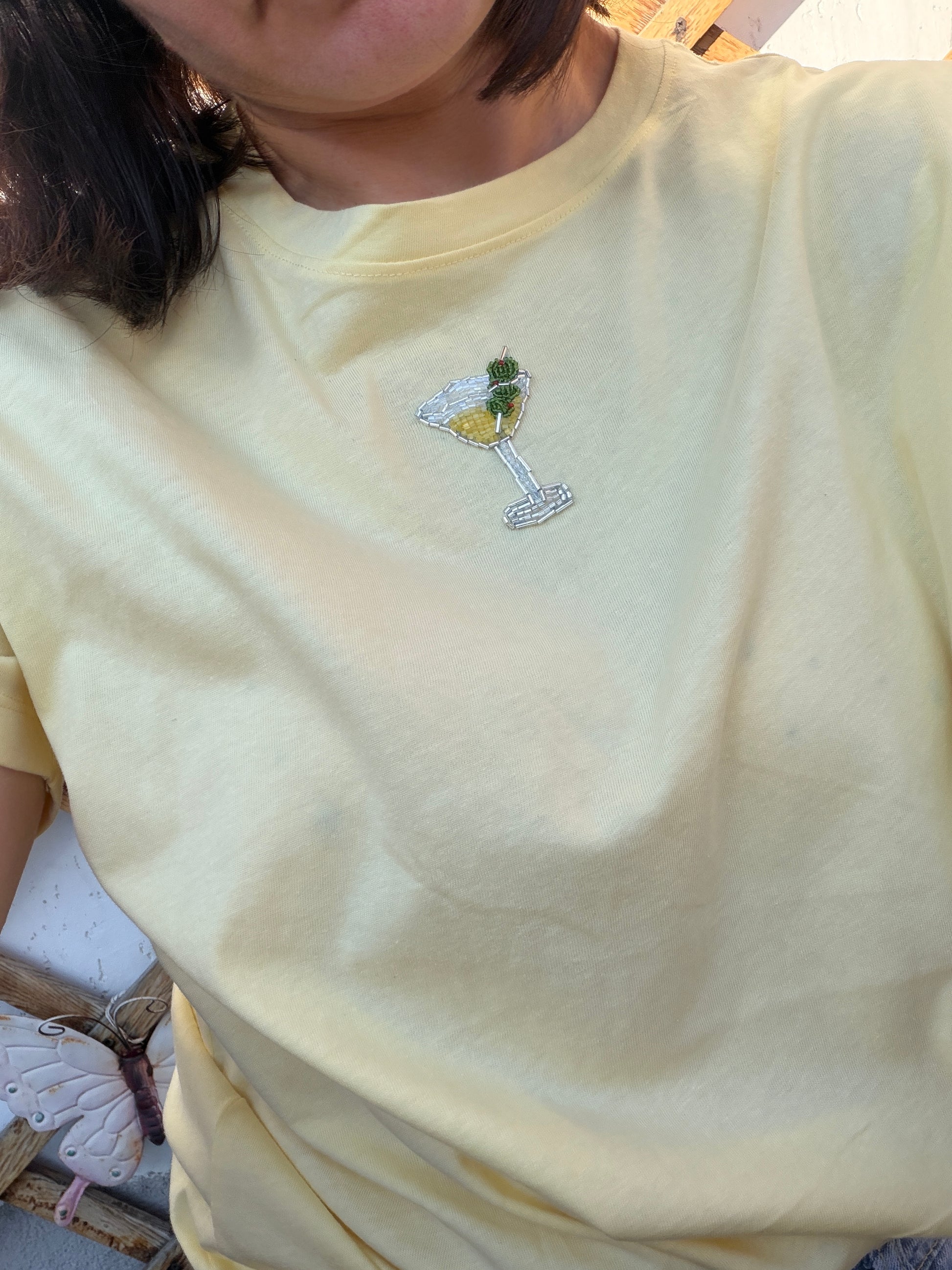 Light yellow t-shirt with a martini glass design on a plain background
