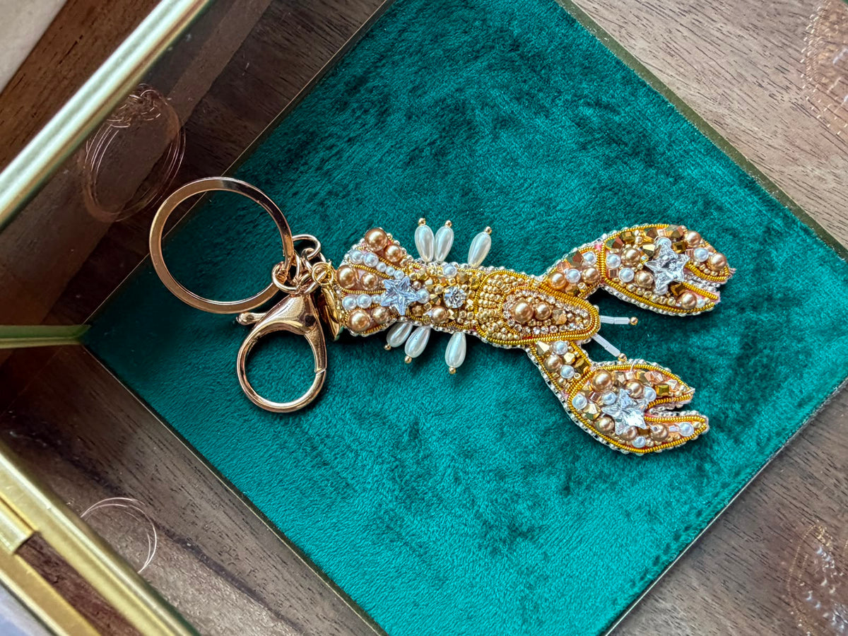 Handmade gold lobster keychain decorated with sparkling crystals and pearl beads, a unique ocean-inspired handbag and key accessory.